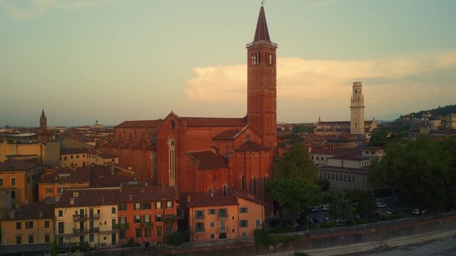 Aerial view of Saint Zeno Basilica in Verona with tall brick bell tower and historic buildings at sunset, capturing the charm of the old town and warm evening light.
