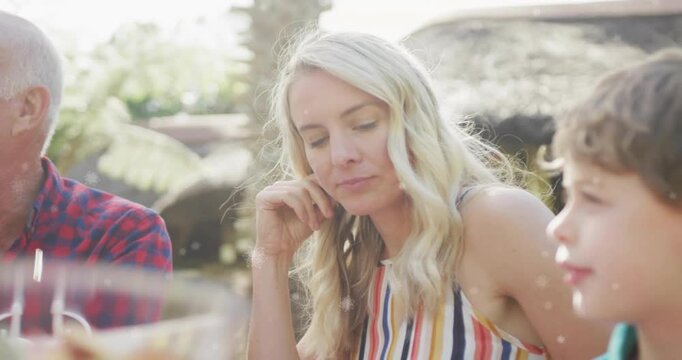 3-generation family sitting, boy reaching into fruit sparking mother speaking about lifestyle