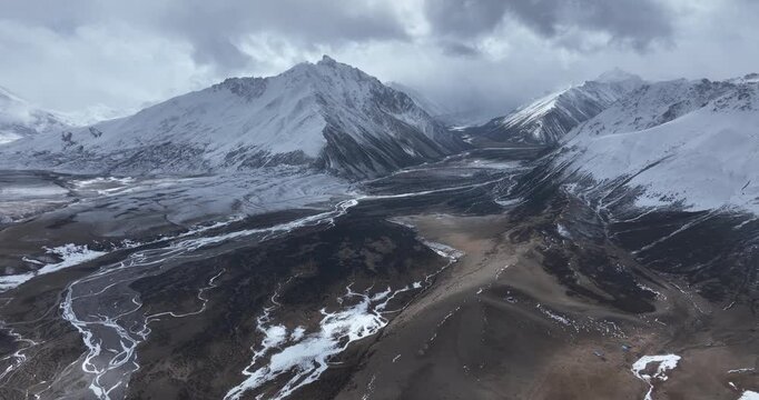 Aerial footage of beautiful high altitude snowcapped mountains and forest landscape