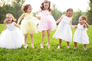 Naklejka premium Five Happy Little Girls Holding Hands and Jumping Together Outside