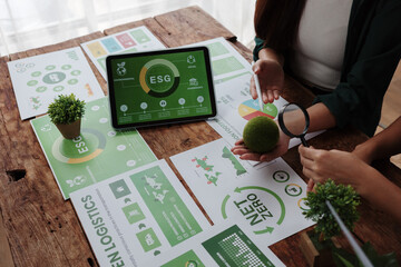 Businesswomen analyzing esg report with magnifying glass and green globe