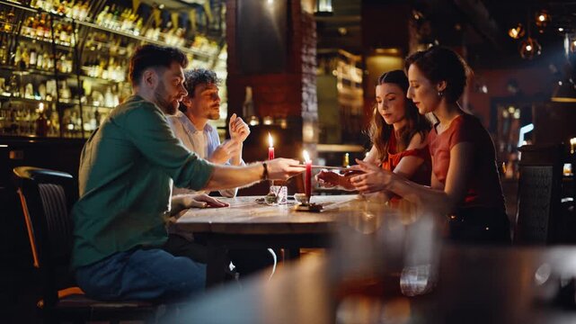 Men giving menu women at night date in restaurant. Group young people meeting