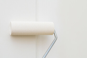 Small roller painting wall in white color applying smooth even layer during renovation