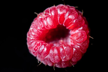 Close-up shot of a raspberry showing the details of the red fruit's texture. Black background.