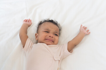 Newborn baby health care. Newborn baby in diaper lying crying on white blanket