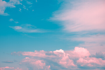 Drifting pink and white cumulus clouds float across a vibrant blue sky, crafting a dreamy and surreal atmosphere that evokes feelings of tranquility and inspiration