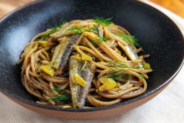 Spaghetti With Sardines and Lemon Served in a Black Bowl at a Dining Table