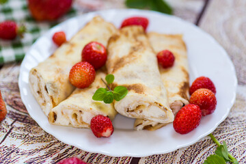 Sweet pancakes with cottage cheese and strawberries on top, on a wooden table