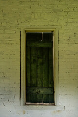 A green-shuttered window in an old brick building