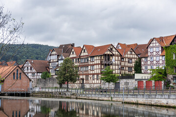 Fototapeta premium Historic German architecture with half timbered buildings, riverside reflections, and cloudy sky background
