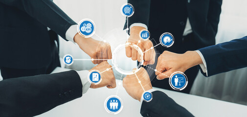 A diverse business team engages in a fist bump, surrounded by KPI icons that symbolize teamwork and success in a modern office setting, representing collaboration and achievement. Amity