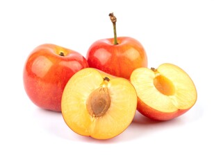 Ripe plums displayed with a halved fruit showing the pit on a white surface