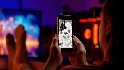 Person reading cute maid girls black and white manga comic on smartphone over shoulder view