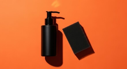 Obraz premium Black Dispenser Bottle With Sponge On Orange Background
