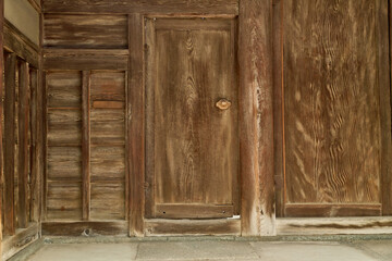 伝統的な日本建築の背景用素材。経年で色褪せた木製の門扉とくぐり戸。