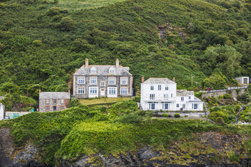 Clifftop coastal houses on lush green hillside, rugged shoreline village, scenic UK coast