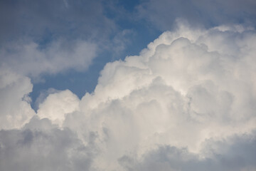Fluffy white clouds drifting against a bright blue sky during a sunny afternoon