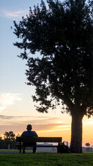 Person on bench at sunrise in park