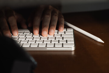 Person typing on a computer keyboard in a well-lit workspace during daytime