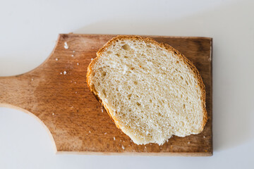 Freshly cut slice of bread on a wood cutting board in a bright kitchen, highlighting the texture and color of the bread