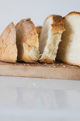 Freshly baked bread on a wooden cutting board with slices gently leaning to the side in a bright kitchen setting