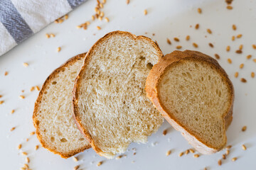 Freshly sliced bread arranged neatly on a white surface with scattered grains in the background, perfect for a simple meal or snack