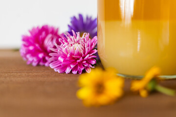 Refreshing drink beside vibrant flowers on a wooden table during a sunny afternoon gathering