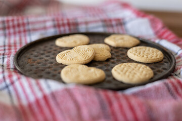 Deliciously baked cookies arranged on a traditional round tray with a checkered cloth backdrop in a cozy kitchen setting