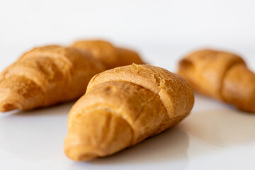 Freshly baked golden croissants arranged neatly on a white surface in a cozy kitchen setting during...