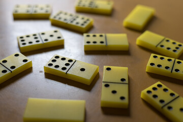 Colorful yellow domino pieces scattered on a wooden table during an afternoon game session with friends