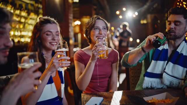 Sport fans clinking beer watching television in dark bar closeup. Smiling people