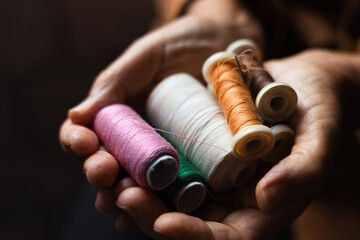 Colorful sewing threads held by hands demonstrating crafting skills in a cozy workshop setting...