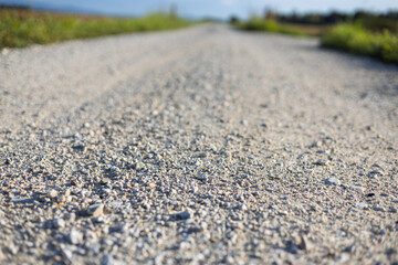 Gravel path stretches towards the horizon under a clear blue sky in a rural area during daylight hours