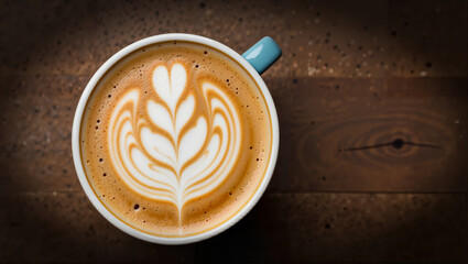 Coffee cup with latte art on wooden table background  