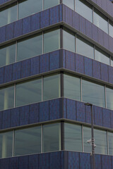 A close-up, low-angle view of a modern building with a curved glass and metal facade on a cloudy day.