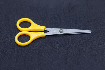 Small Yellow Handled Scissors with Stainless Steel Blades on Black Surface.