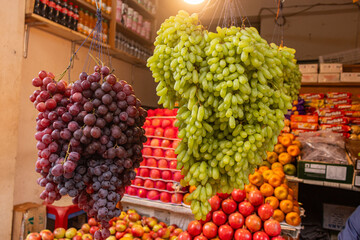 Traditional Open Fruit Shop with Grapes Hanging and Oranges Stacked on Display.