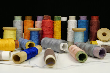 Spools with multi-colored threads on black background, close-up shot