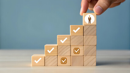 Hand placing final block on staircase of wooden cubes with checkmarks and person icon