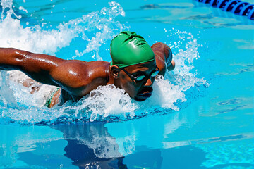 powerful and athletic Black man swims the butterfly stroke during a competition, showcasing his strength, speed, and determination as a professional swimmer