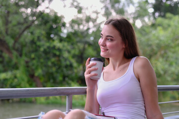 A young woman enjoying a warm beverage while relaxing in nature, embodying peace and serenity.