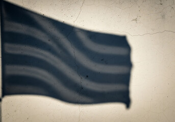 Shadow of a waving flag on a textured, grungy wall