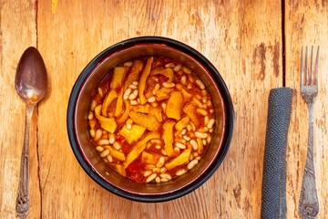 A classic Brazilian dish known as dobradinha, prepared with beef tripe, white beans, and tropical spices, served with traditional farofa made from toasted cassava flour.