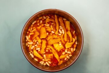 A classic Brazilian dish known as dobradinha, prepared with beef tripe, white beans, and tropical spices, served with traditional farofa made from toasted cassava flour.