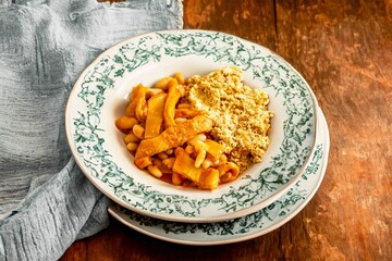 A classic Brazilian dish known as dobradinha, prepared with beef tripe, white beans, and tropical spices, served with traditional farofa made from toasted cassava flour.
