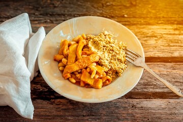 A classic Brazilian dish known as dobradinha, prepared with beef tripe, white beans, and tropical spices, served with traditional farofa made from toasted cassava flour.