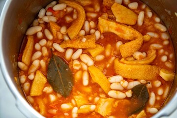 A classic Brazilian dish known as dobradinha, prepared with beef tripe, white beans, and tropical spices, served with traditional farofa made from toasted cassava flour.