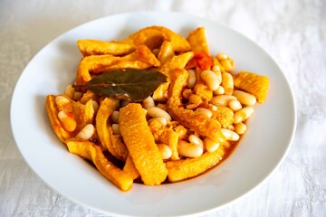 A classic Brazilian dish known as dobradinha, prepared with beef tripe, white beans, and tropical spices, served with traditional farofa made from toasted cassava flour.
