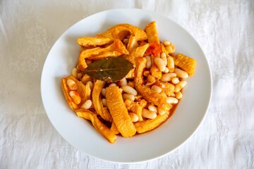 A classic Brazilian dish known as dobradinha, prepared with beef tripe, white beans, and tropical spices, served with traditional farofa made from toasted cassava flour.