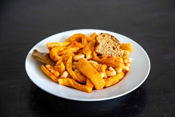 A classic Brazilian dish known as dobradinha, prepared with beef tripe, white beans, and tropical spices, served with traditional farofa made from toasted cassava flour.